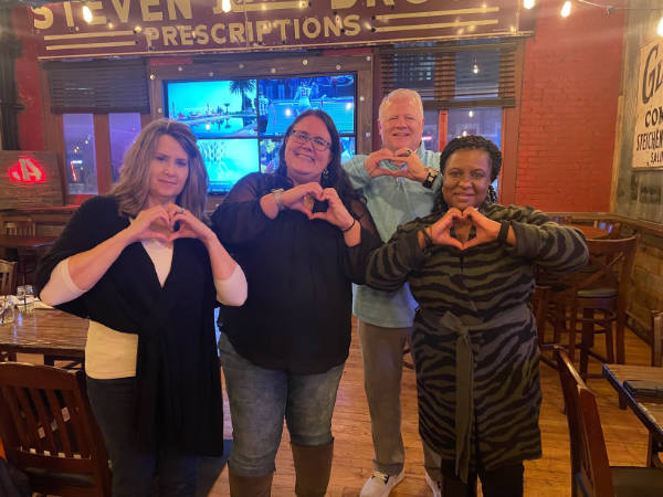 Group of people making the heart symbol with their hands.
